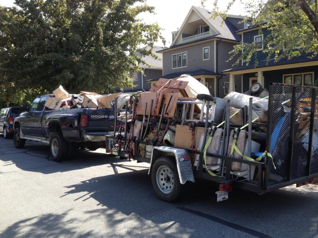 Vehicles carrying junk and hauling materials drive away from a site, clearing debris and waste.