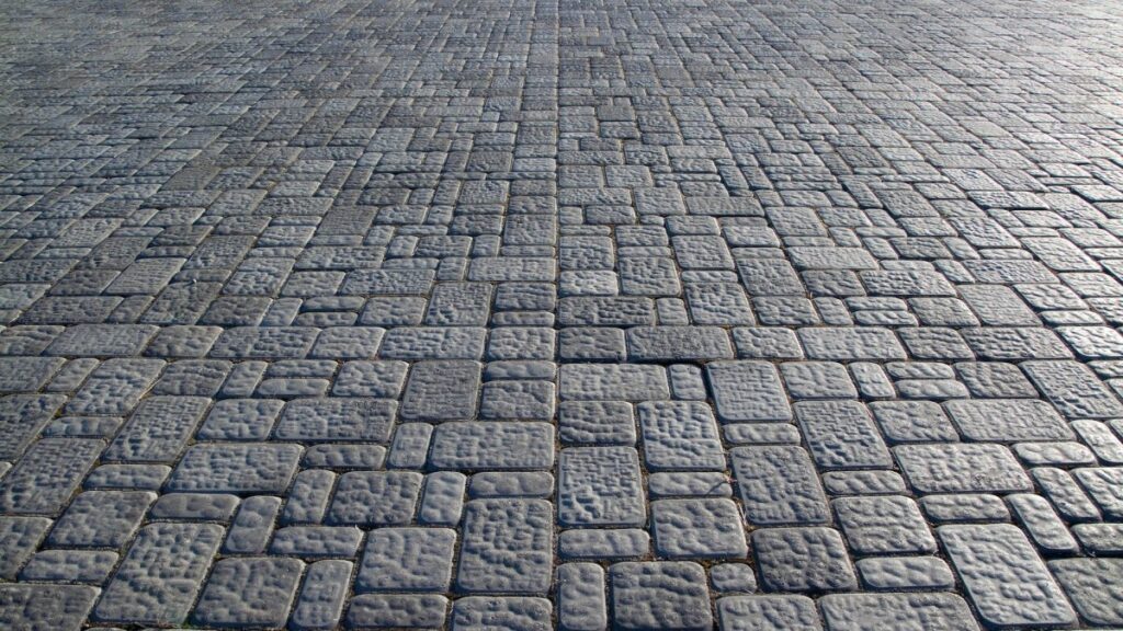 *   Image: A close-up, perspective view of a cobblestone pavement.
    *   Details: Grey/blue stones of various rectangular s