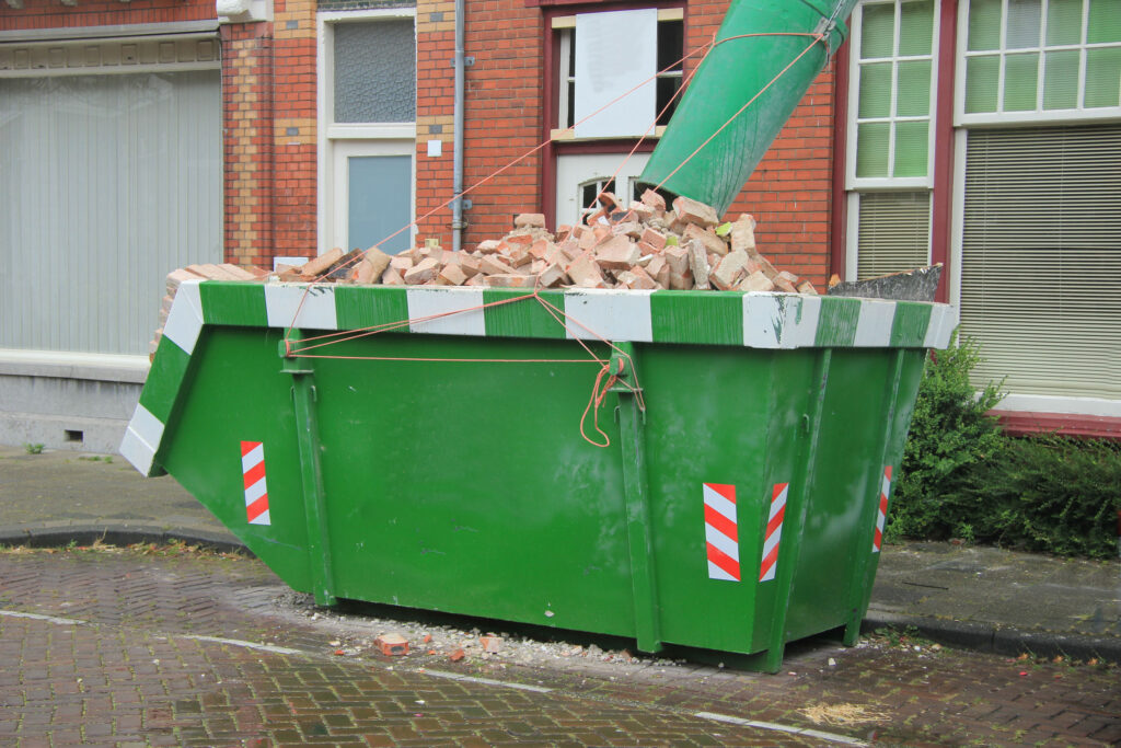 *   Image: A large green construction dumpster (skip) filled with bricks.
    *   Details:
        *   Green dumpster with wh