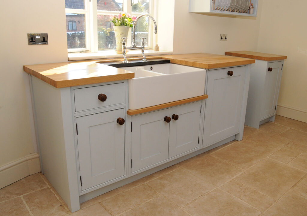 Light blue kitchen cabinets with wooden countertops and a white farmhouse sink.