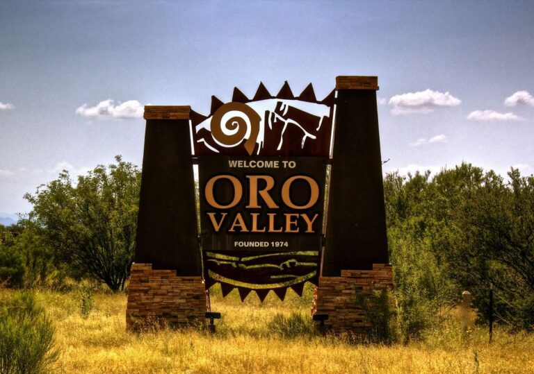 Welcome to Oro Valley sign featuring stylized metal art, stone pillars, and desert landscaping.