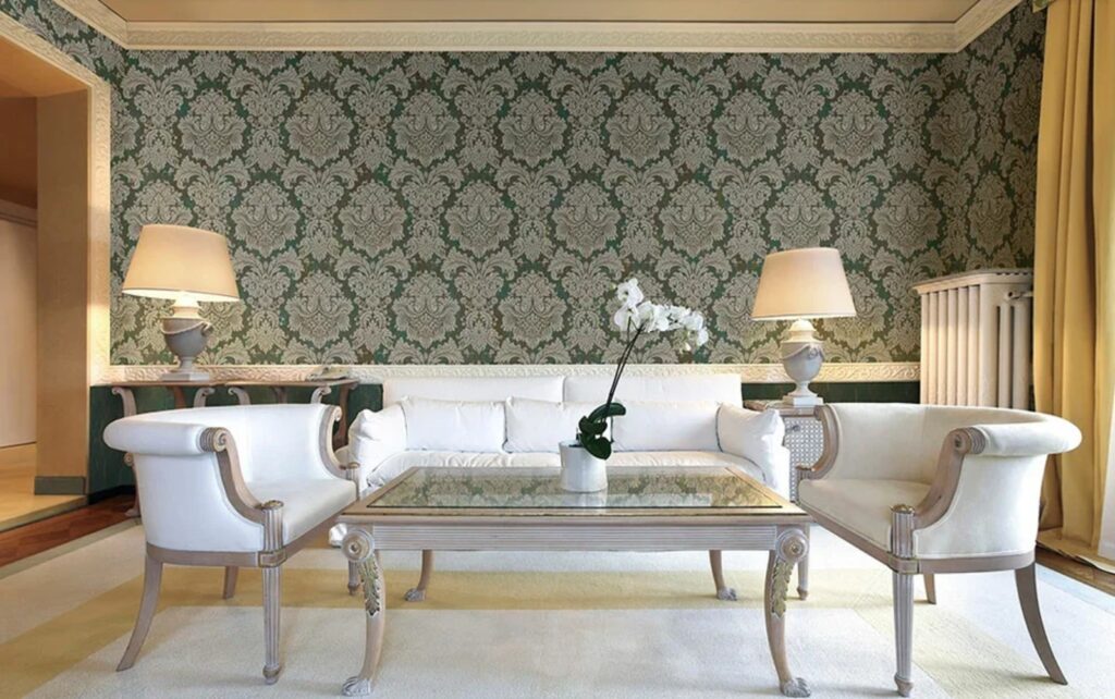A living room with white sofas, two armchairs, a glass coffee table with an orchid, and green damask wallpaper.