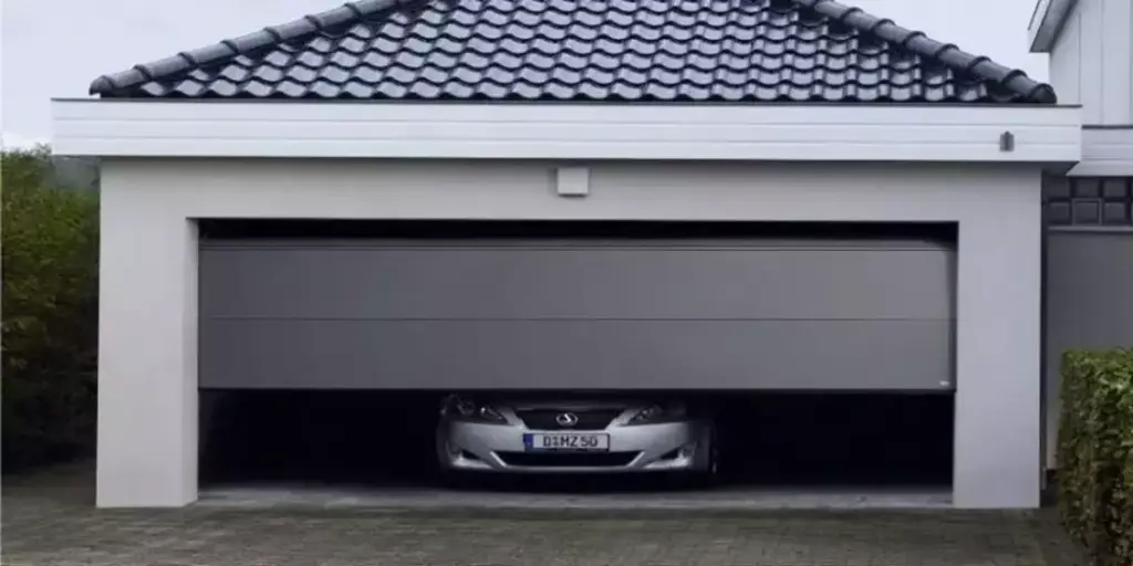 Front view of a silver car inside a white garage with a partially open grey door.