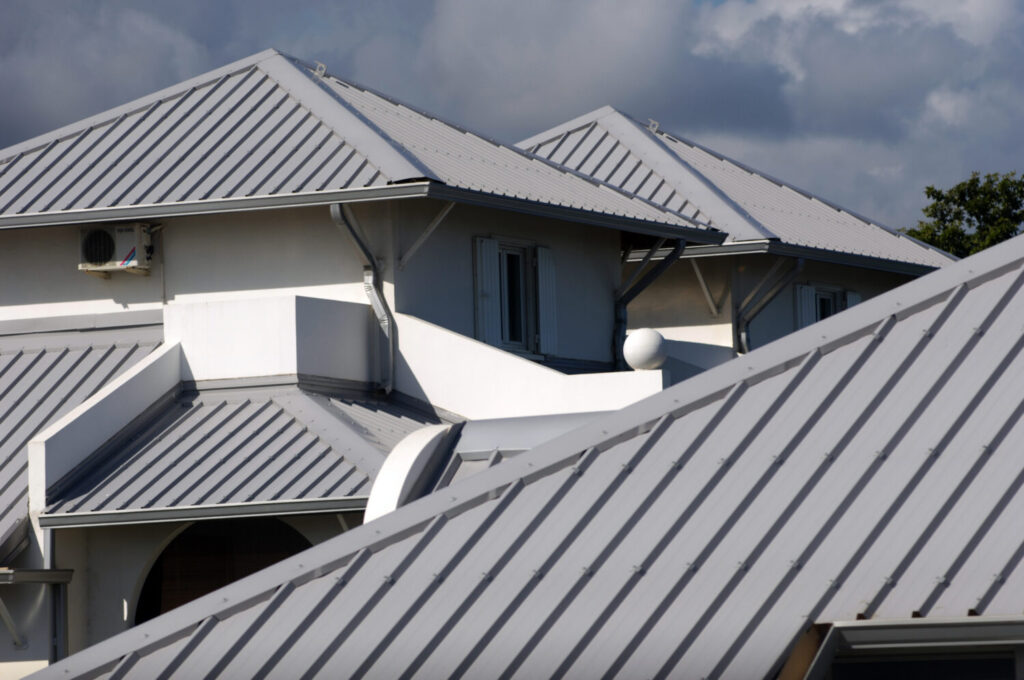 White buildings with light grey corrugated metal roofs under a cloudy sky.