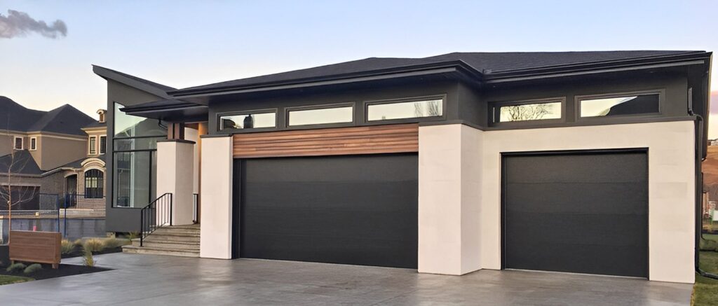 Modern home exterior with dark grey garage doors, cream walls, wood accents, and a sleek black roof.