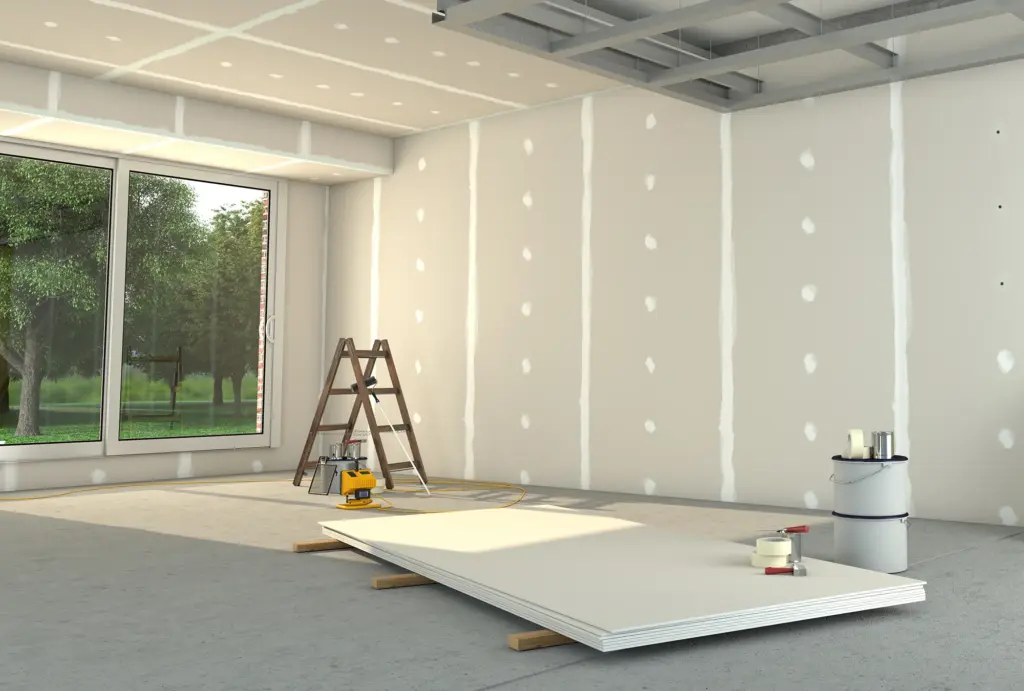 A room under construction with bare drywall, a ladder, construction tools, and a large window looking out at trees.