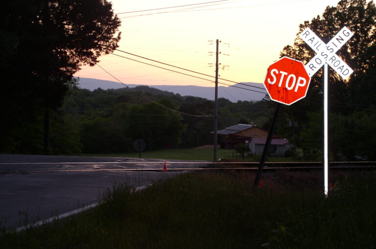 Stop sign and railroad crossing sign at a rural intersection during sunset.