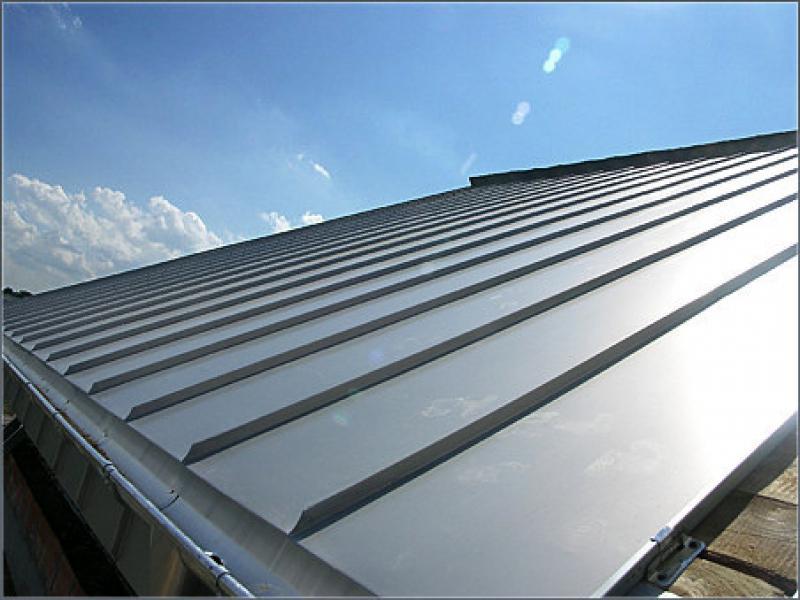 Silver ribbed metal roof under a bright blue sky.