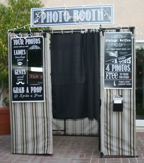 A vintage-style photo booth with black curtains, chalkboard-style signs, and string lights.