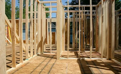 Wooden frame of a house under construction showing wall studs and subflooring.