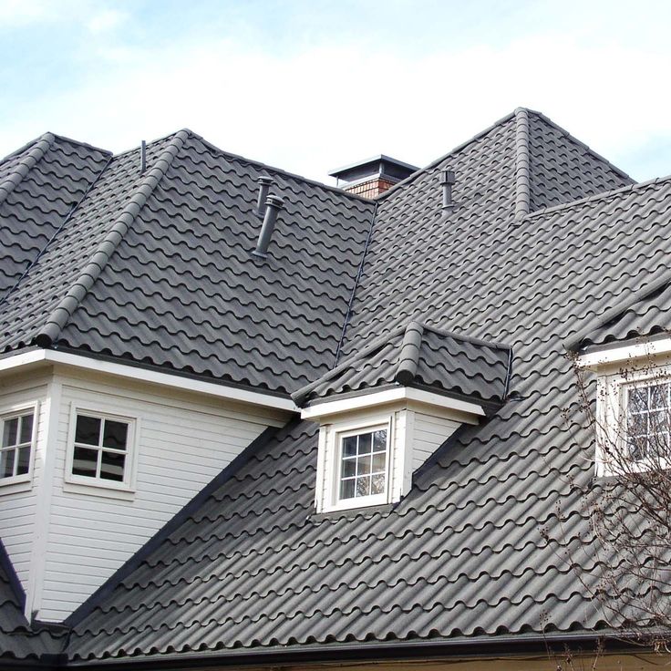 Dark grey wavy roof tiles with white dormer windows.