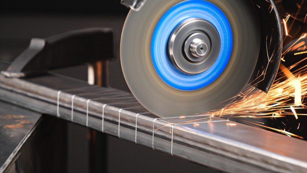 Angle grinder cutting into a metal beam, producing a spray of sparks.