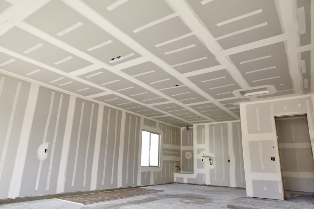 New construction room featuring walls and ceiling covered in taped and mudded drywall with a single window.