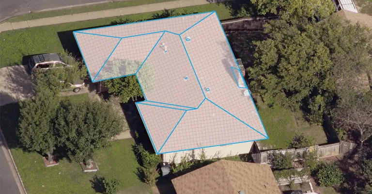Aerial view of a residential roof with blue outlines mapping roof planes and a measurement grid.
