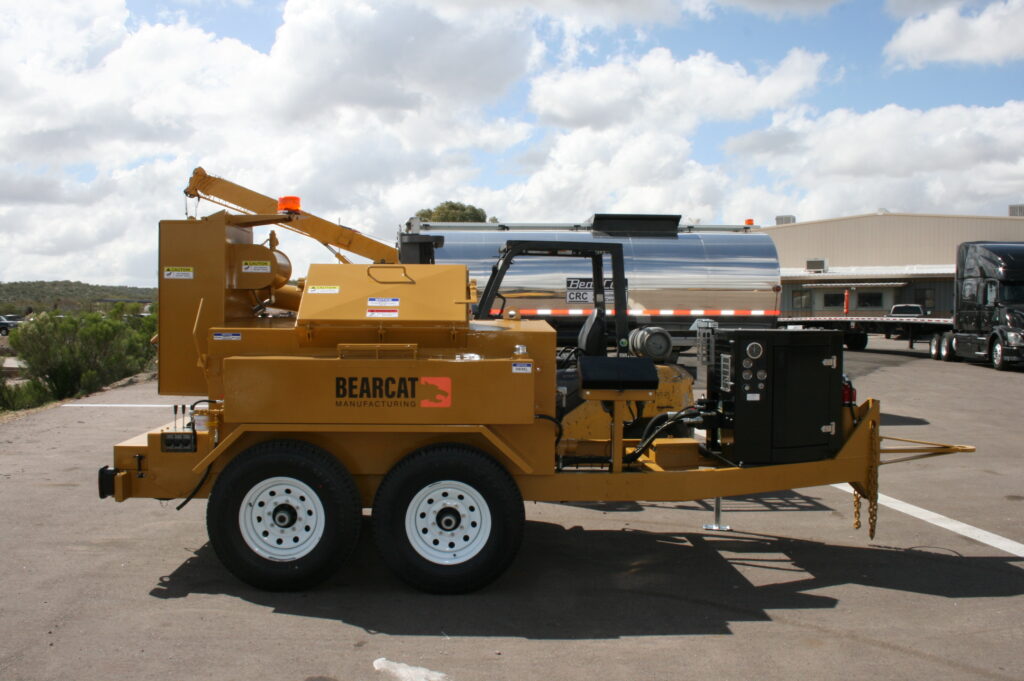 A yellow Bearcat Manufacturing trailer with an operator seat and control panel, parked outdoors on an asphalt lot.