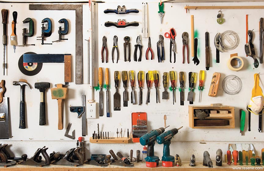 Organized workshop wall hanging various woodworking tools, including hammers, chisels, pliers, and power drills.