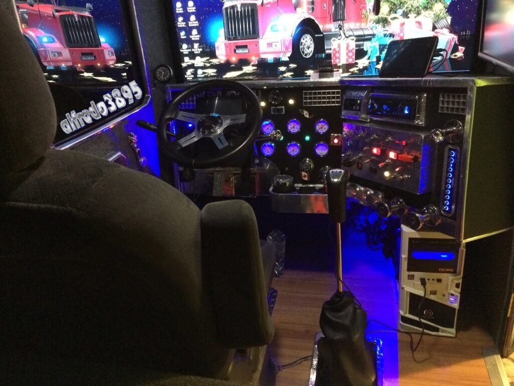 Custom truck driving simulator cockpit with steering wheel, gear shifter, illuminated dashboard gauges, and monitor displays.