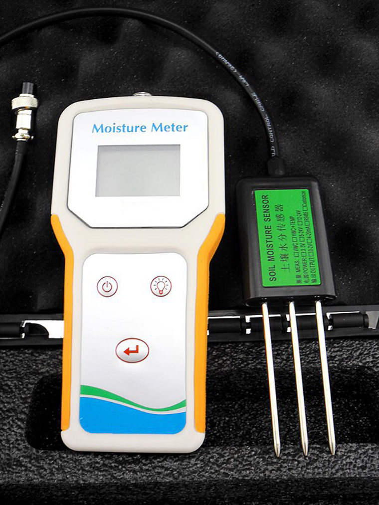 Handheld digital moisture meter with a connected three-pronged soil moisture sensor.