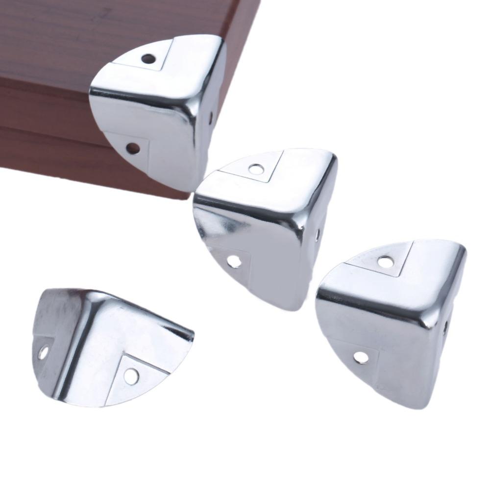 Four silver metal corner protectors for furniture or boxes, with one shown installed on a wooden corner.