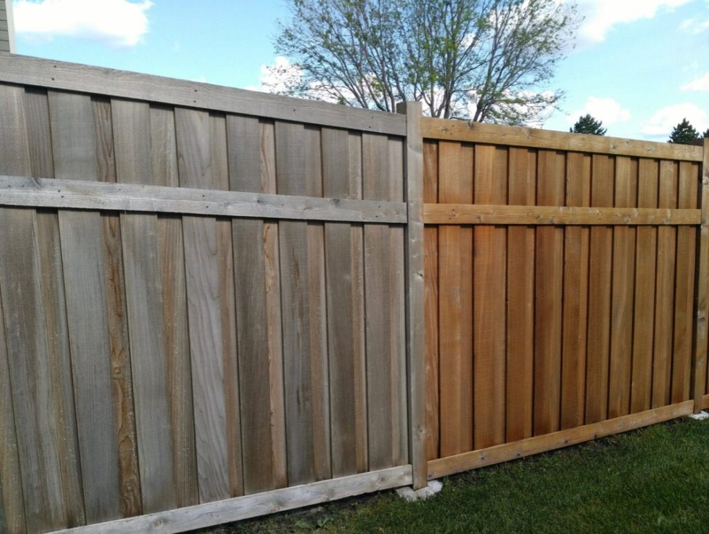 Wooden fence showing a clear contrast between a gray, weathered section and a freshly stained, warm-toned section.