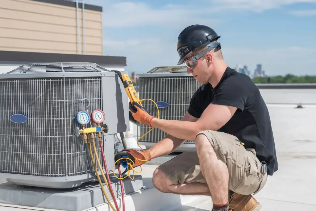 HVAC technician using a multimeter to service a rooftop condenser unit.