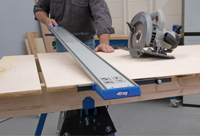 Kreg rip-cut guide and circular saw set up for cutting plywood on a workbench.