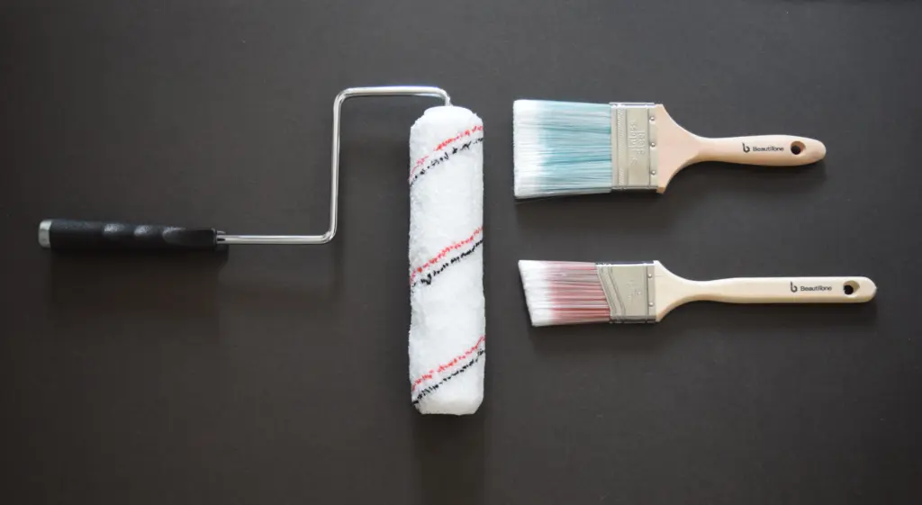 A paint roller and two Beautitone paint brushes arranged on a dark background.