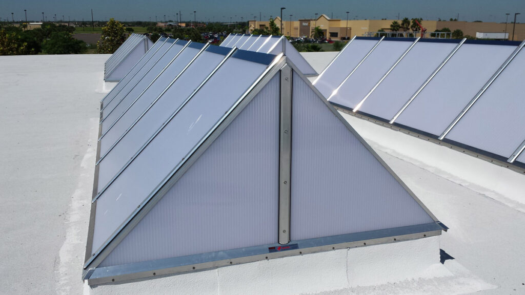 Triangular translucent skylights on a flat white rooftop.