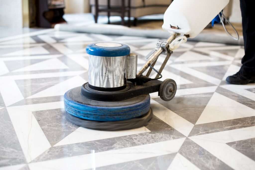 Industrial floor buffer polishing a grey and white geometric marble floor.