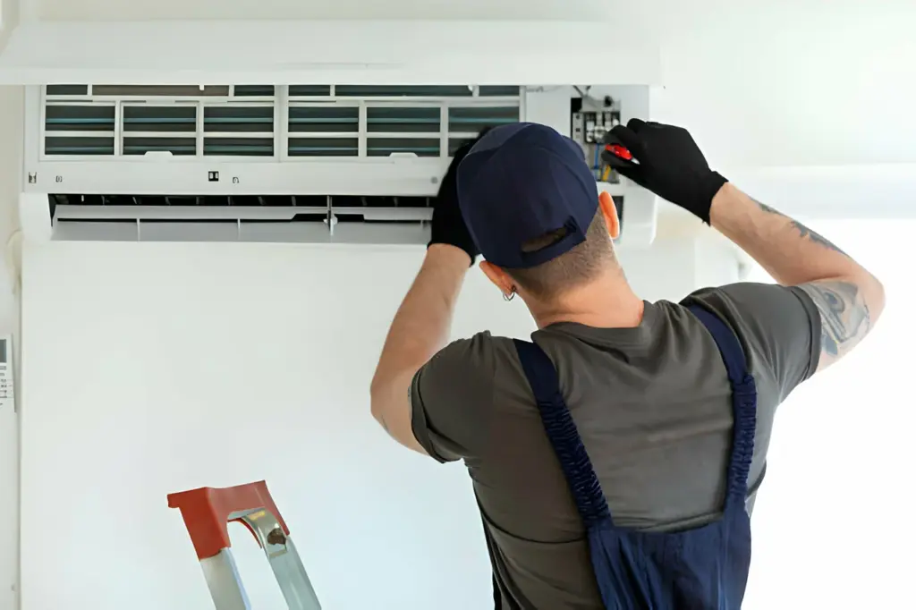 HVAC technician repairing a wall-mounted air conditioning unit.