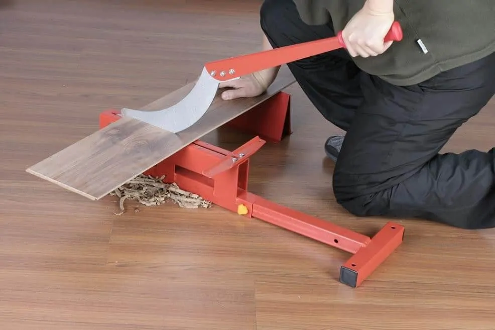 Person using a red manual wood shaver to plane a wooden board.