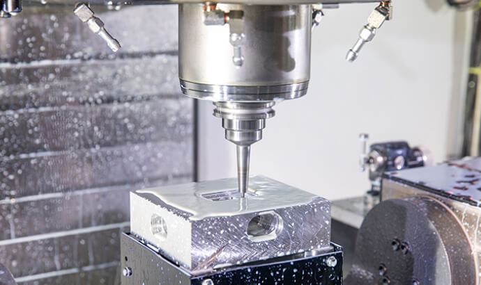 CNC milling machine tool cutting a metal workpiece with cooling fluid.