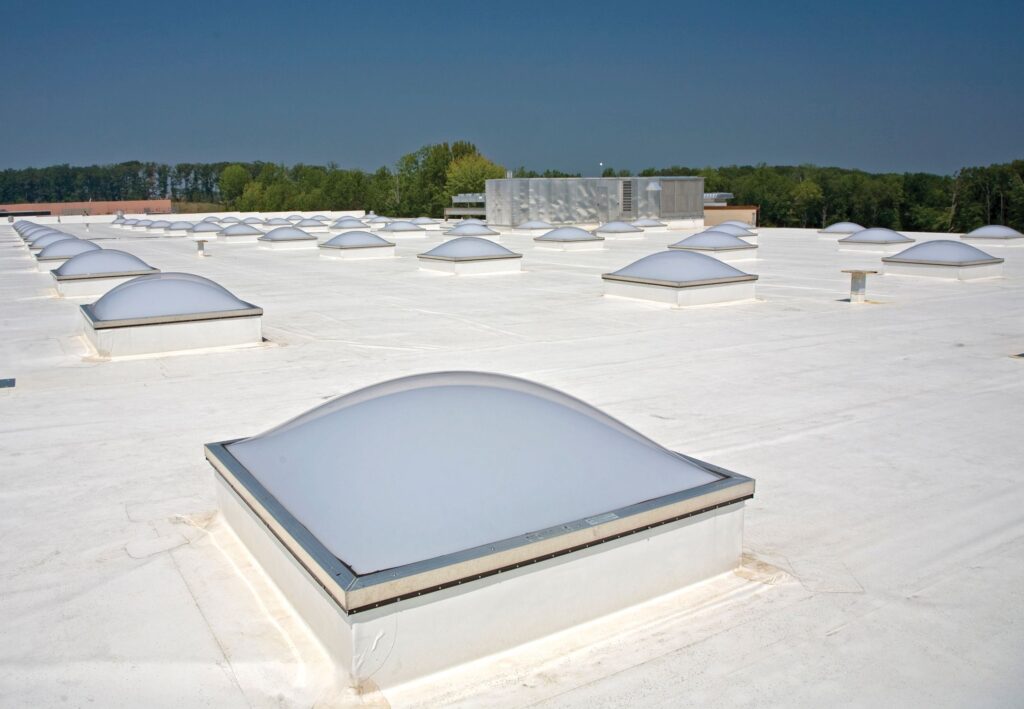 Rows of dome-shaped skylights on a flat white industrial roof.