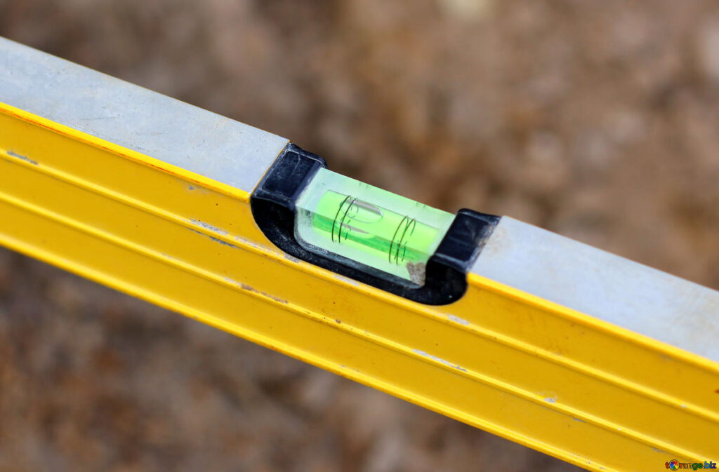Close-up of a yellow spirit level with the bubble centered in the green vial.