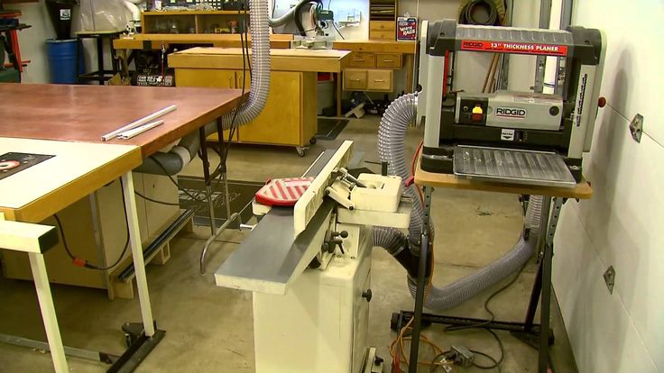 Woodworking shop featuring a Ridgid thickness planer, a jointer, and a workbench with dust collection hoses.