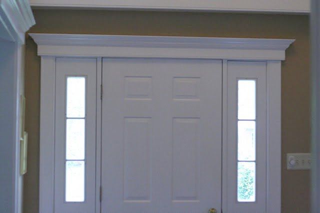 White paneled front door with side windows and decorative white molding.