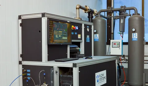 Flow Systems industrial control station with a monitor and two large gray tanks labeled A and B.