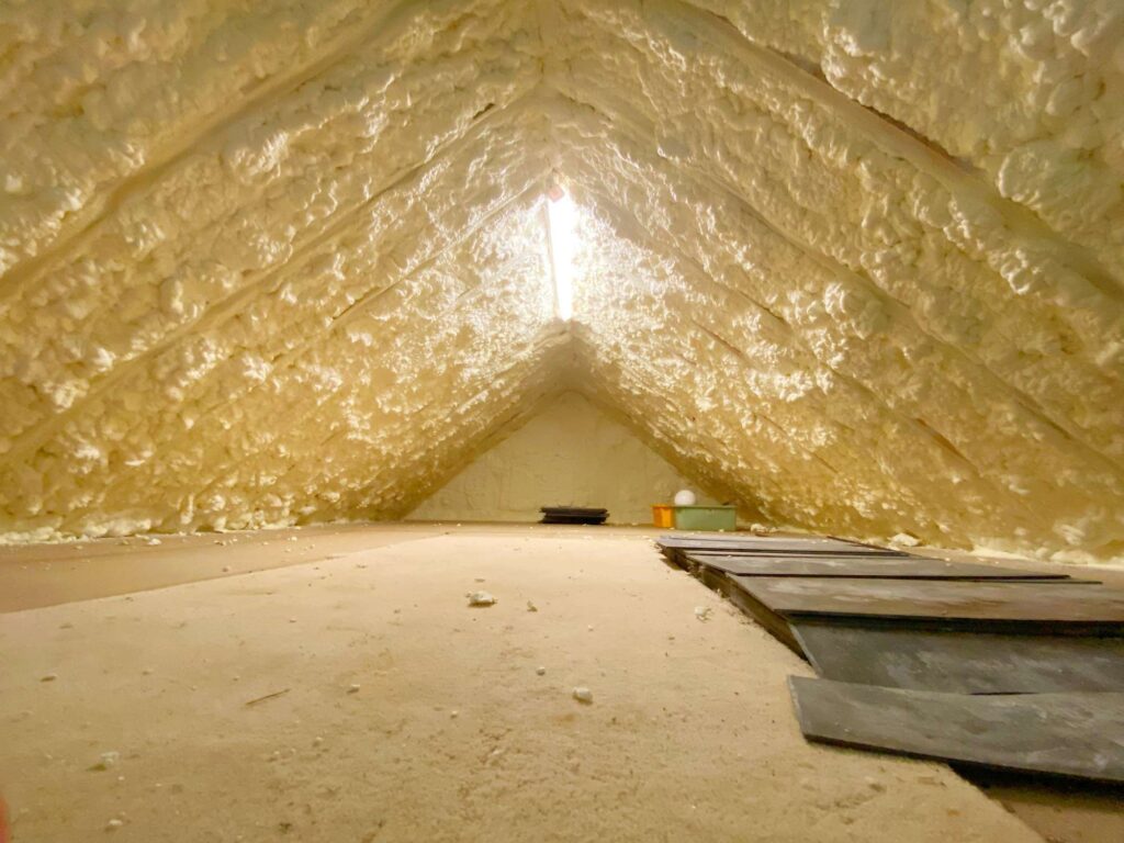 Attic space with textured spray foam insulation on the sloped ceiling.