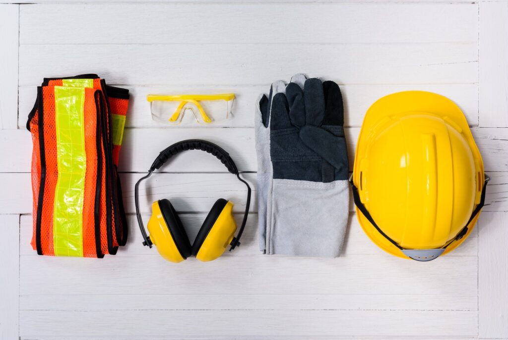 Personal protective equipment (PPE) including a yellow hard hat, safety glasses, ear muffs, gloves, and high-vis vest.