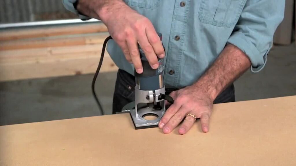 Person using a handheld router on the edge of a wooden board.
