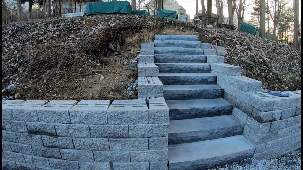 New stone steps integrated into a retaining wall built into a dirt hillside.