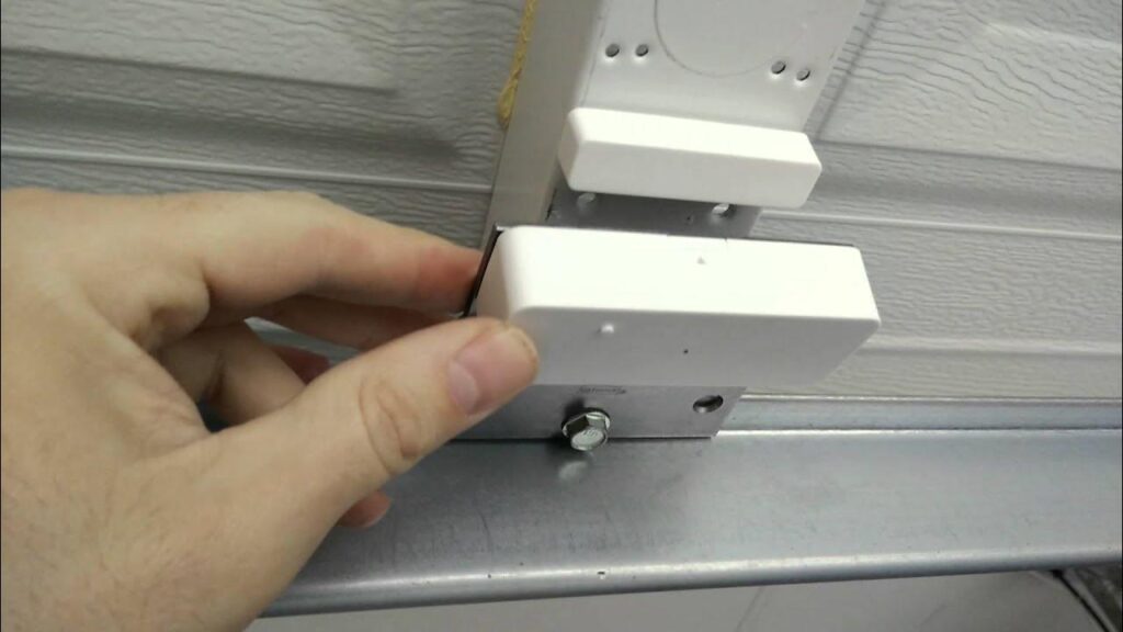 A hand fitting a white plastic block into a metal bracket on a silver rail.