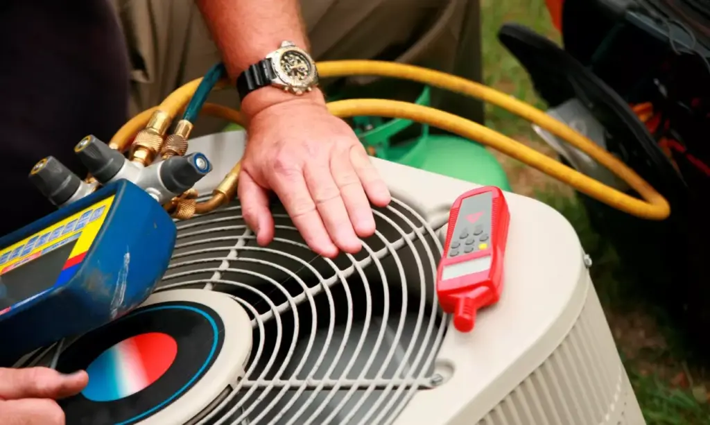 Technician servicing an AC condenser unit using manifold gauges and a leak detector.