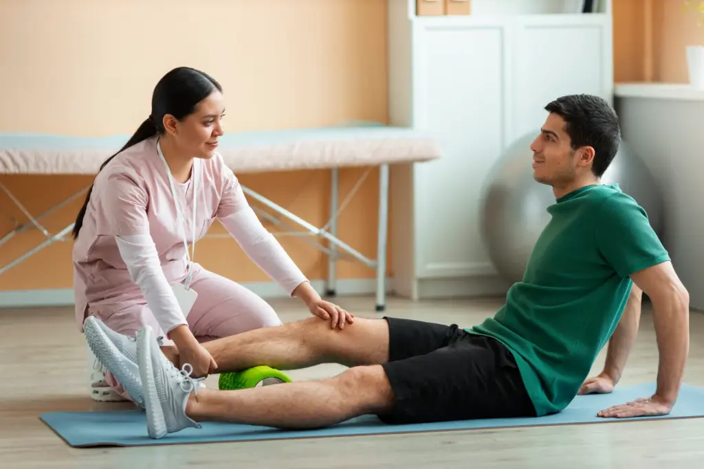 Physical therapist assisting a patient with a foam roller exercise during a rehabilitation session.