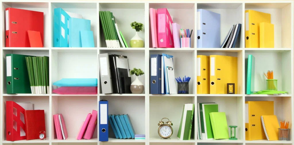 White shelving unit neatly organized with colorful binders, notebooks, folders, and office accessories.