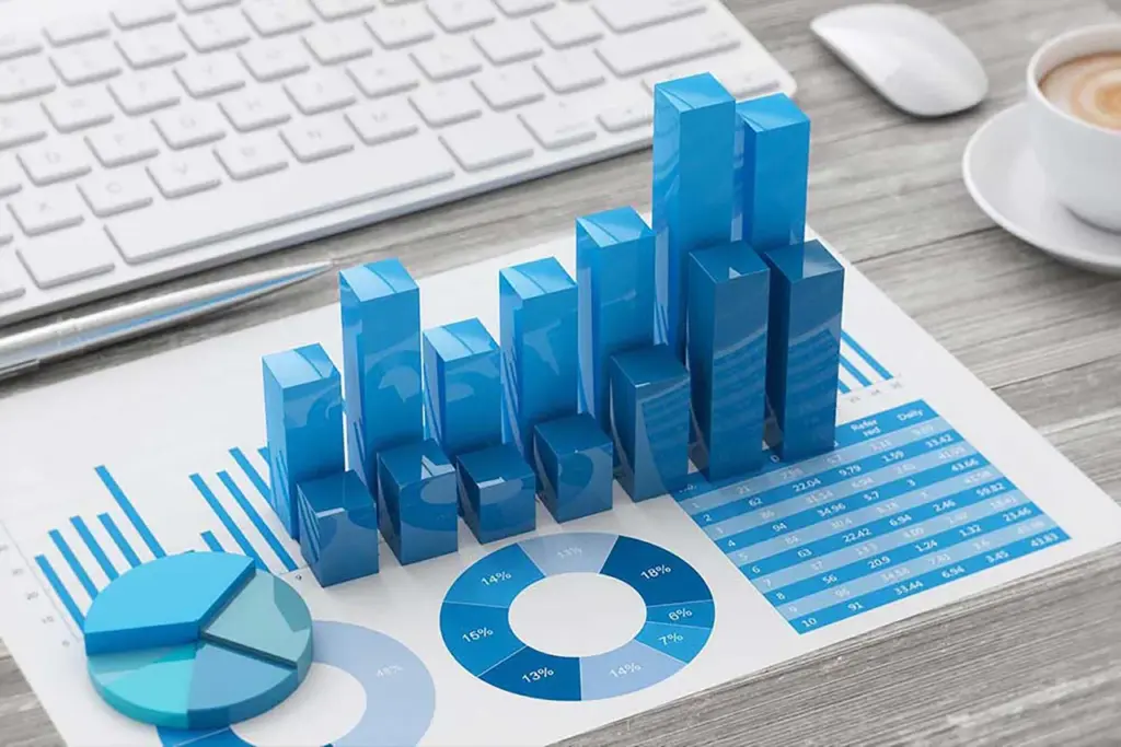 3D blue bar charts, pie charts, and data tables on a document next to a computer keyboard and coffee cup.