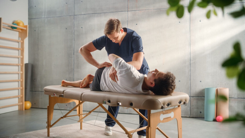 Physical therapist performing a manual therapy adjustment on a patient lying on a treatment table.