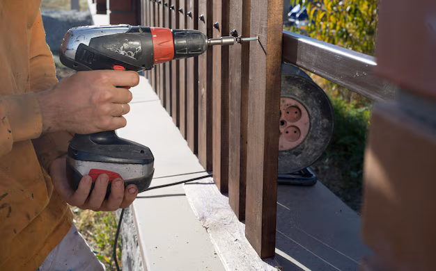close up of hand screewing wood plank to metal construction building a wooden fence with a drill and screw 635416 2011