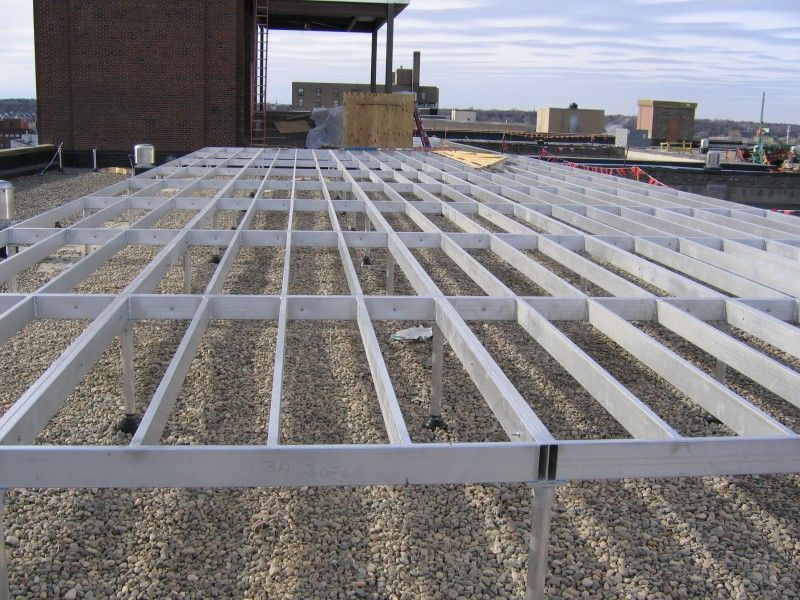 Metal pedestal grid system for a raised floor installed on a gravel rooftop.