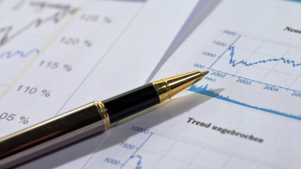 Black and gold pen resting on financial documents with line graphs and percentage data.